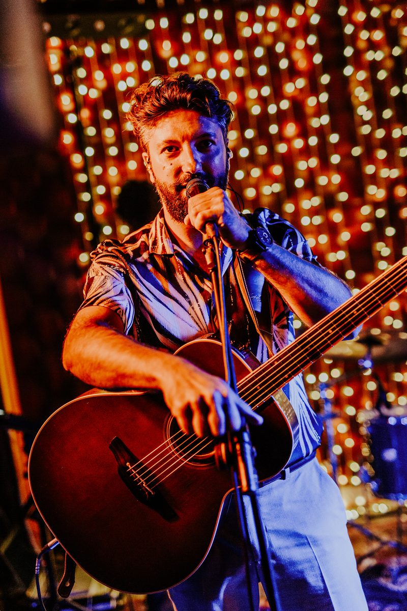 Acoustic guitar and vocals under string lights at a wedding